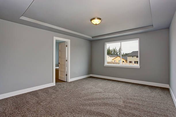 Empty bedroom with gray walls, carpet, and window, light fixture on the ceiling.