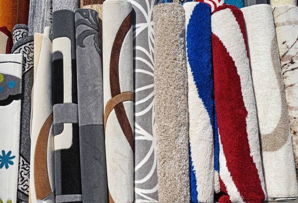 Rolled-up carpets in various colors and patterns, displayed upright in a store.
