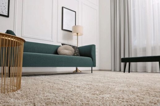 Teal sofa, gold table, and fluffy rug in a modern, white-walled living room.
