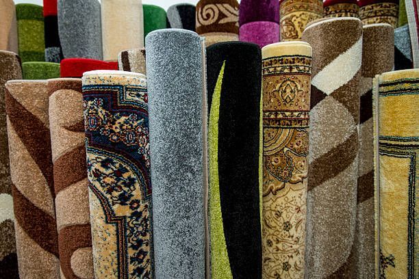 Rolled carpets in various colors and patterns displayed in a store.