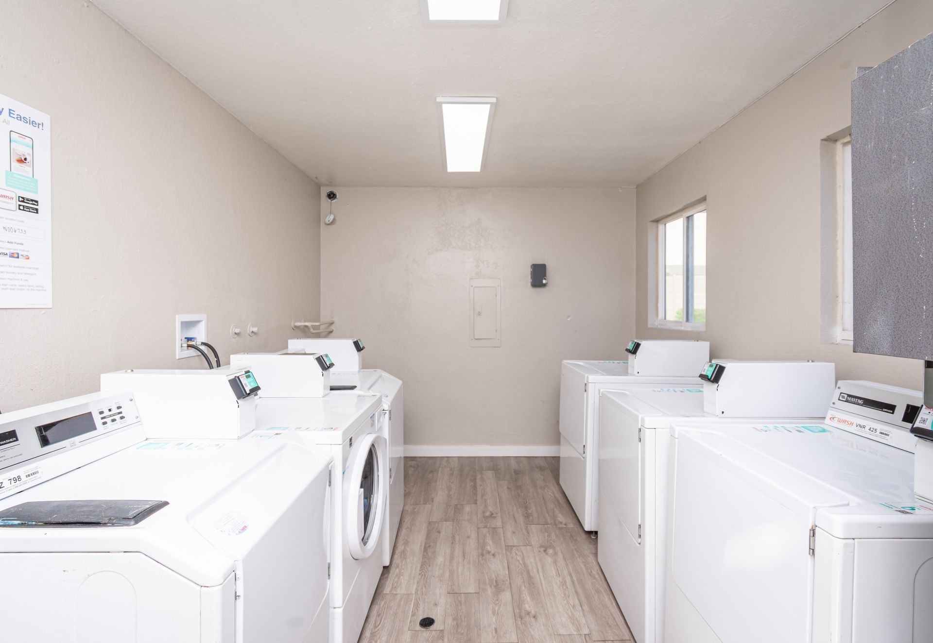 A laundry room with a lot of white washers and dryers.