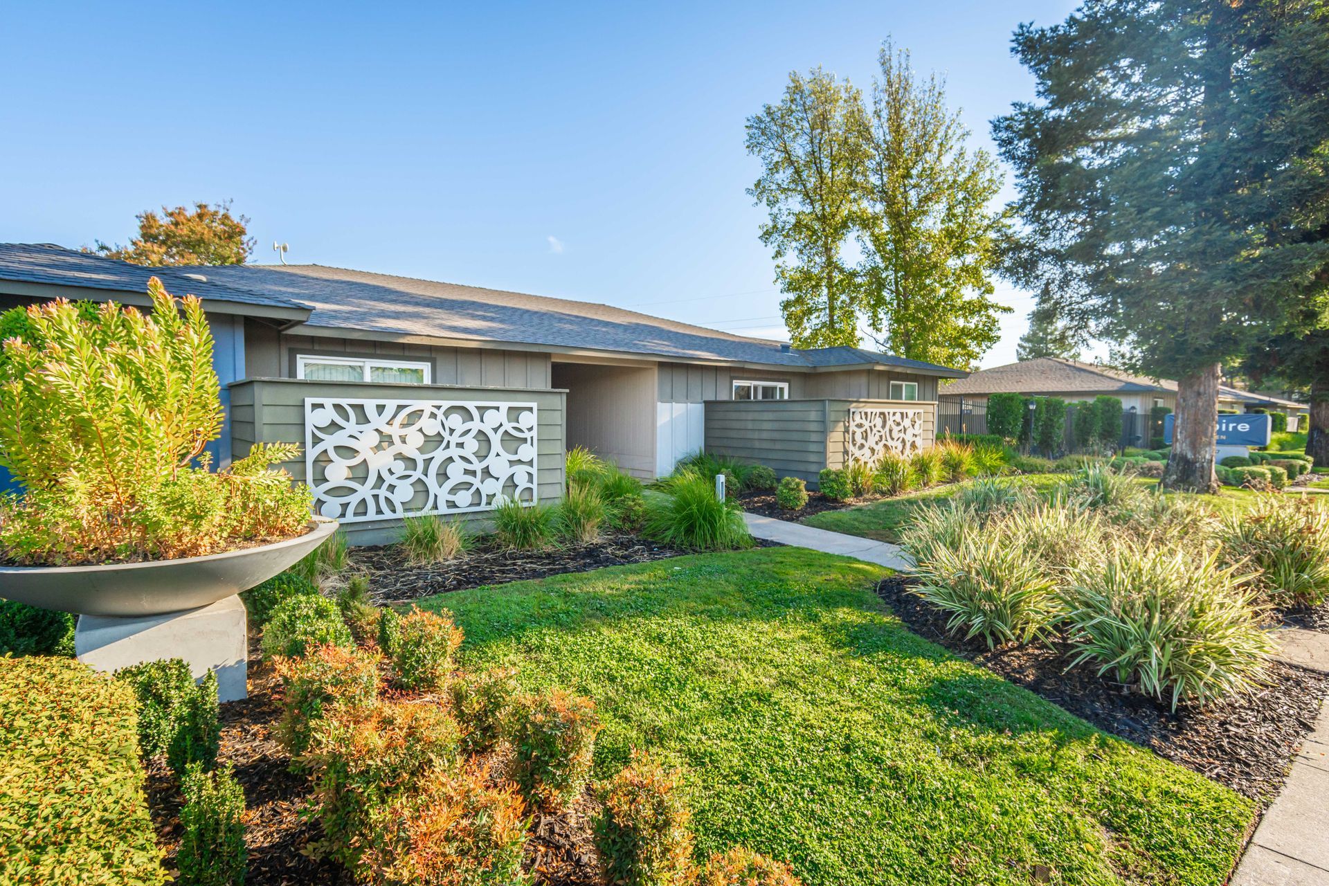 A house with a lush green lawn and a walkway leading to it.