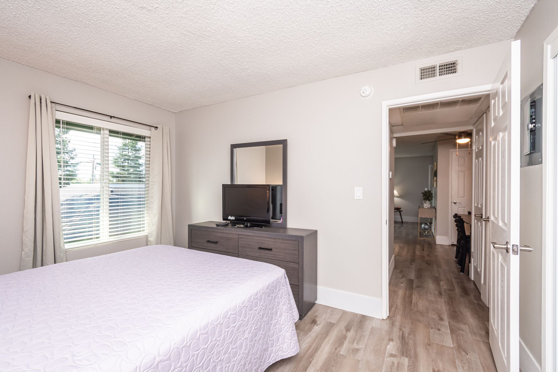 A bedroom with a bed , dresser , mirror and television.