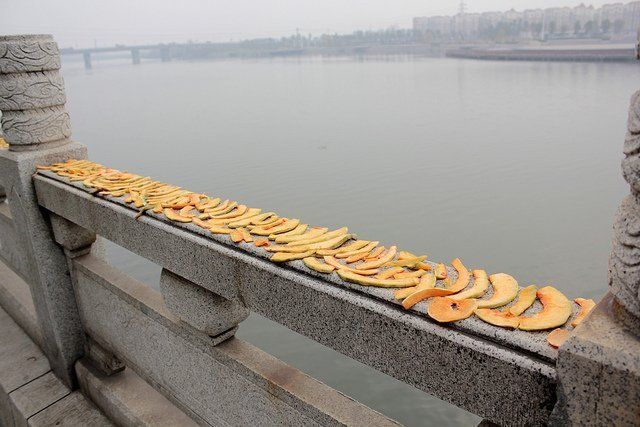 Frutas siendo secadas en baranda de un puente y fondo nuboso