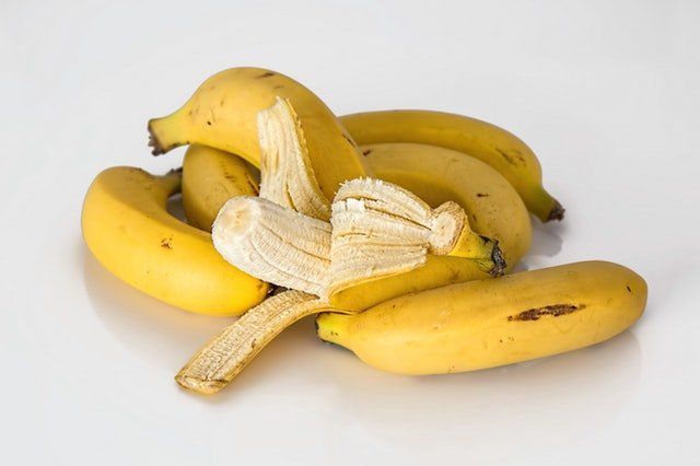 Conjunto de bananos, uno a medio pelar