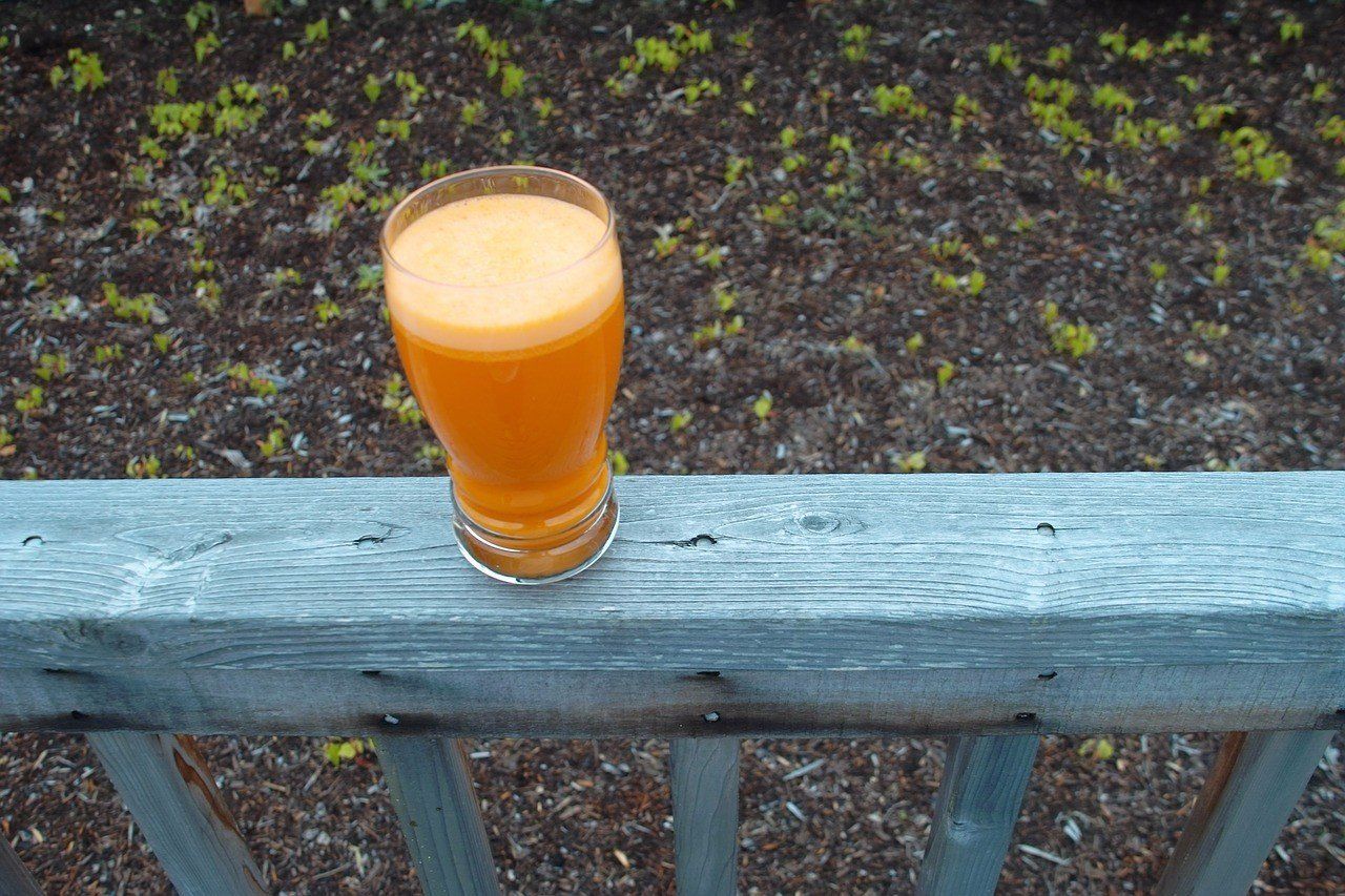 vaso de jugo de zanahoria sobre puerta de jardin