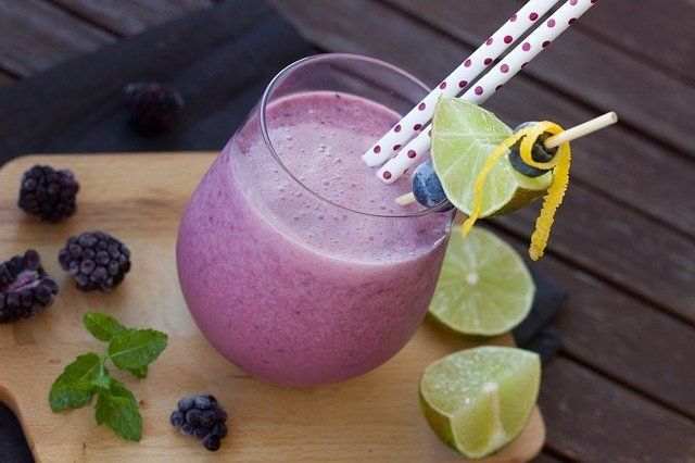 Bebida de mora en vaso con moras y limones al lado