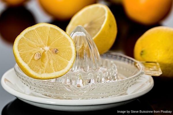 Exprimidor de limón de vidrio con un limón cortado encima
