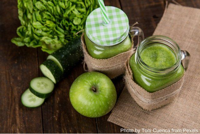 Acercamiento a vasos con jugos verdes junto a ingredientes
