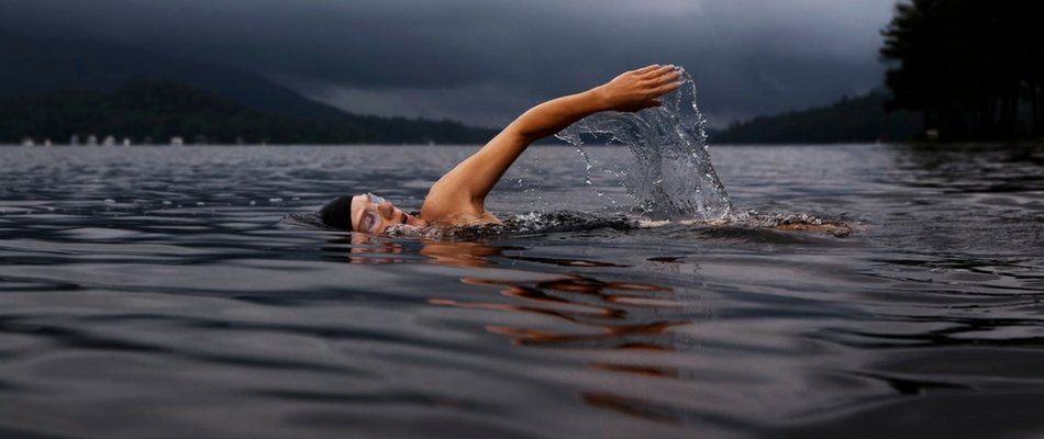 nadador en agua oscura y cielo nublado