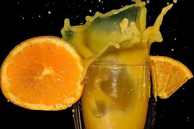 Vaso de jugo de naranja salpicando sobre una rebanada de naranja