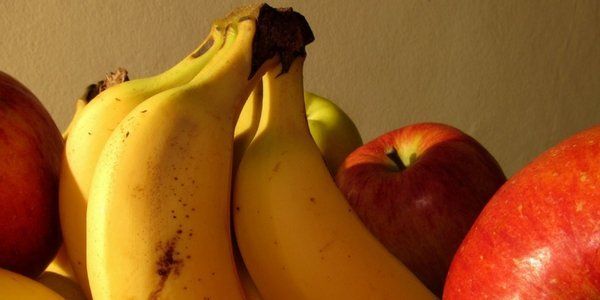 closeup de bananos con manzanas rojas