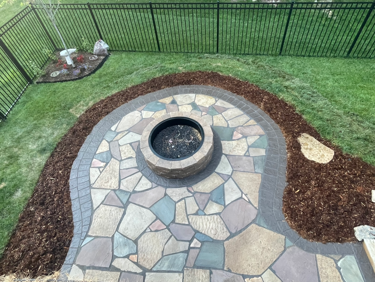 There is a fire pit in the middle of a stone patio.