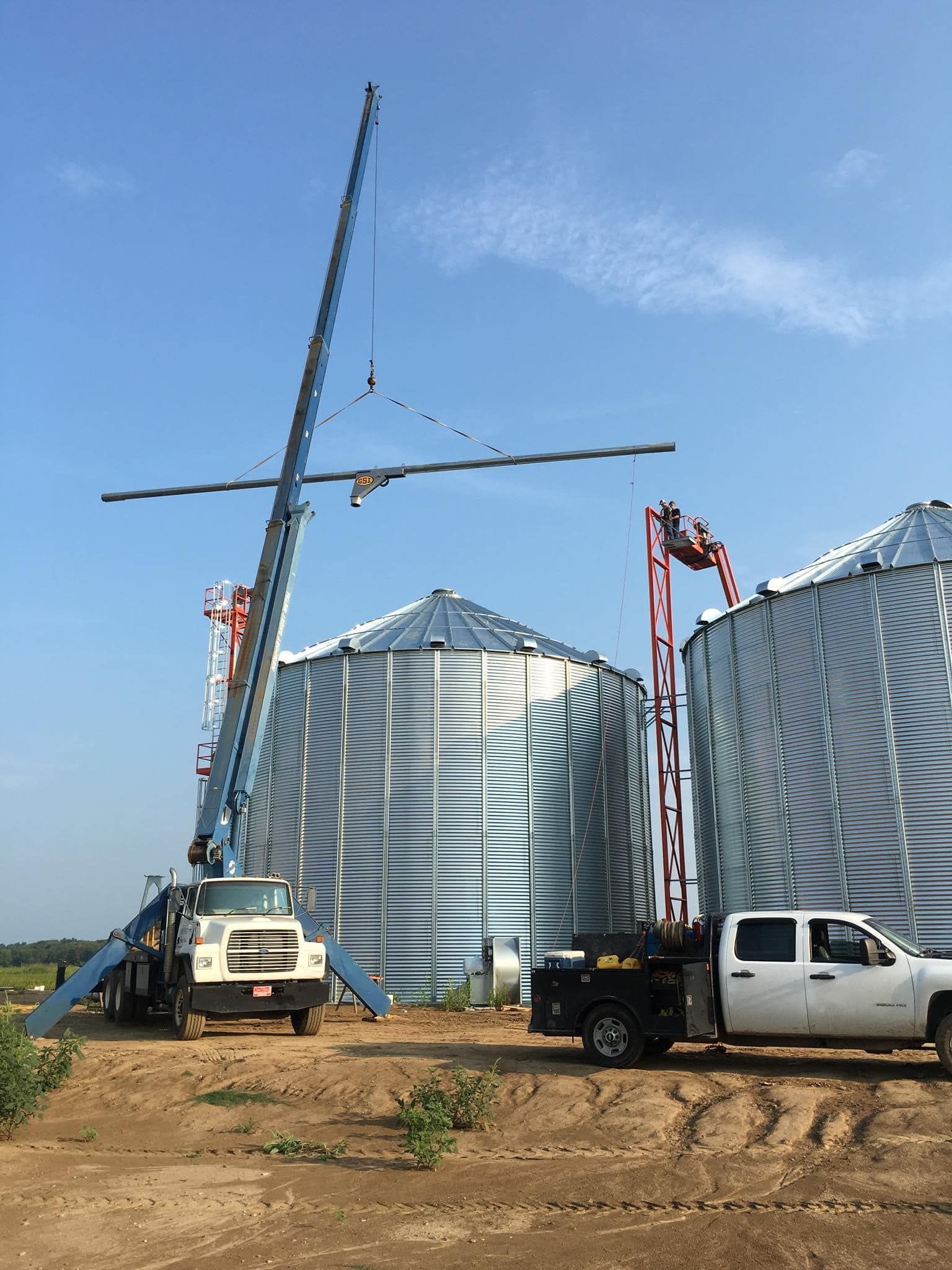 A truck and a crane are parked in front of a grain silo.