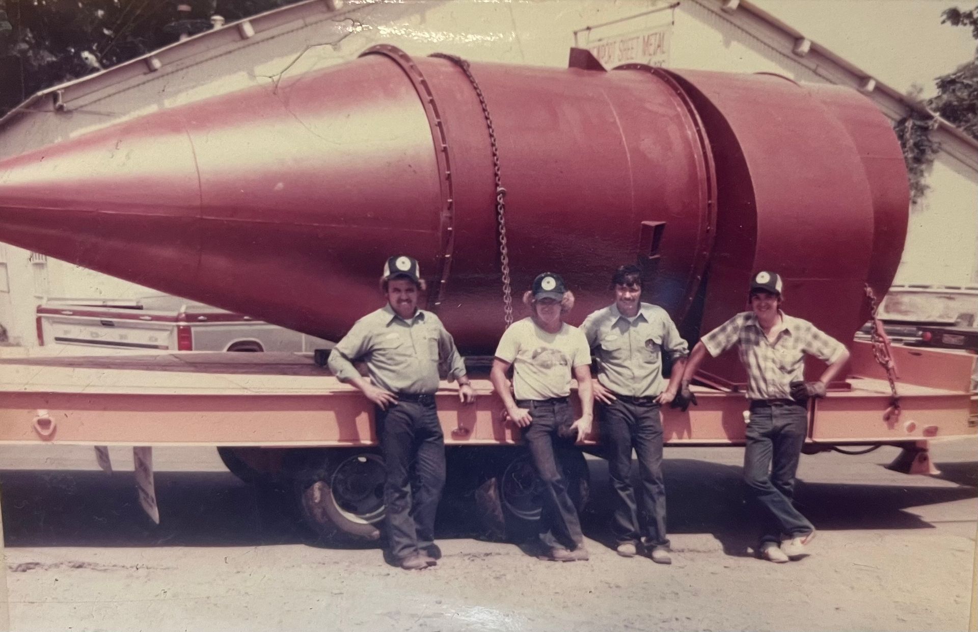 A group of men standing in front of a large red object