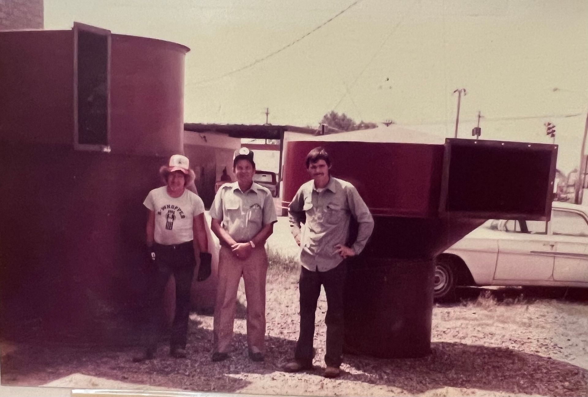 A group of men are standing in front of a large red object