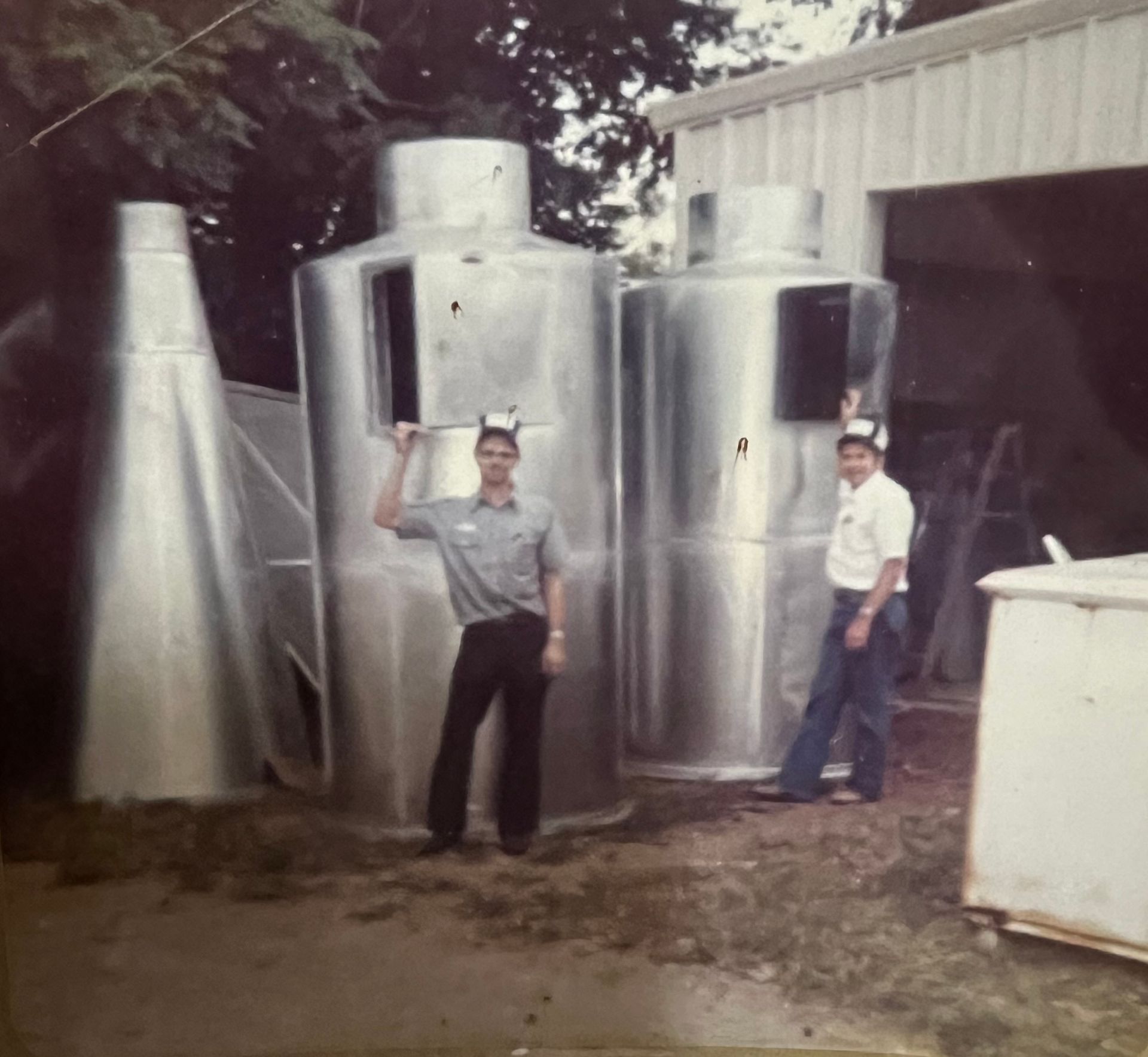 Two men are standing in front of a metal structure