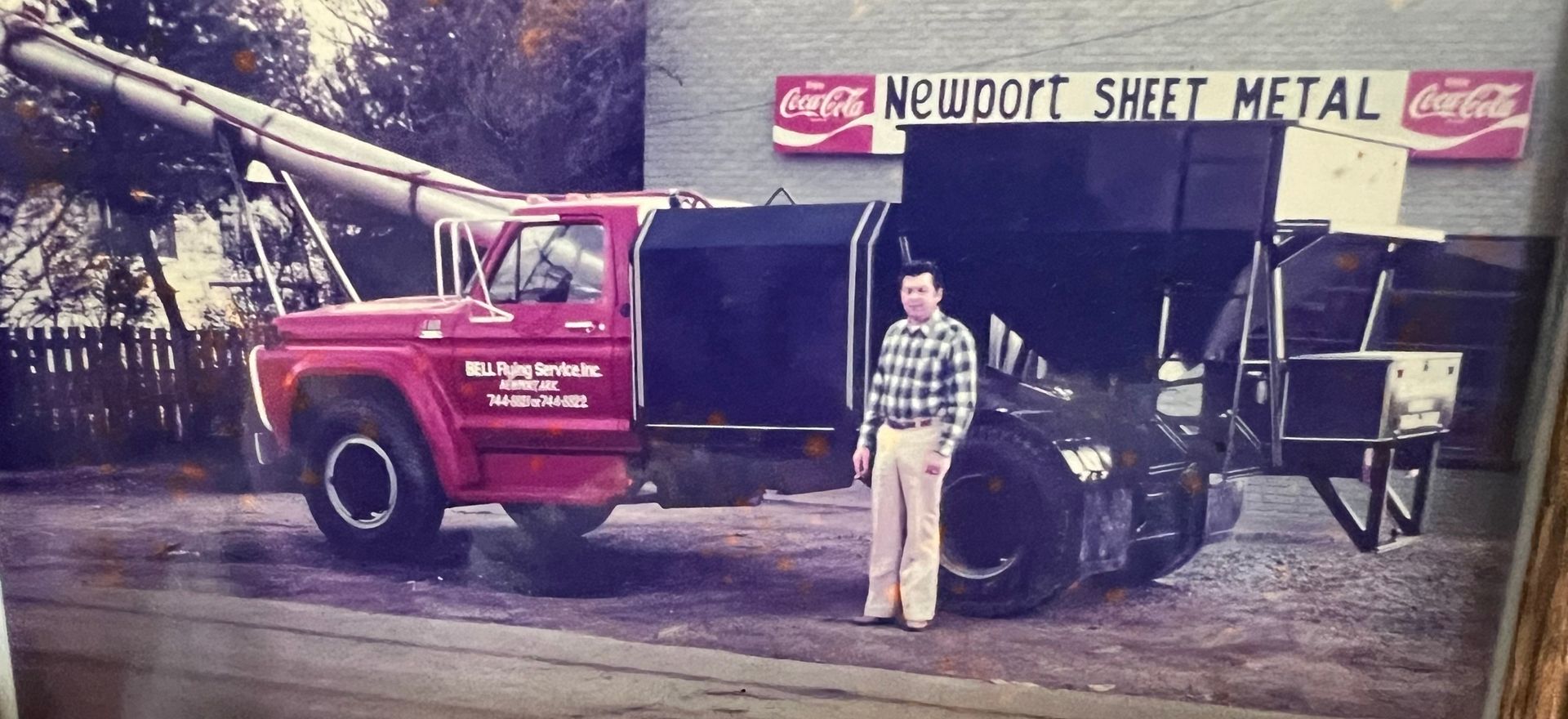 A man stands in front of a truck that says newport sheet metal
