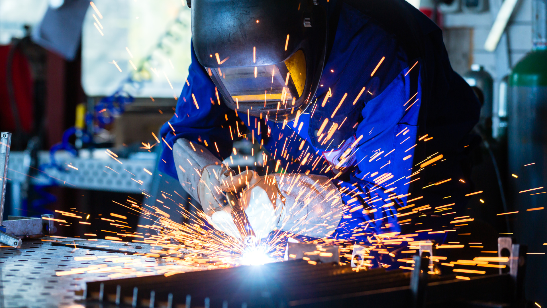 A man is welding a piece of metal in a factory.