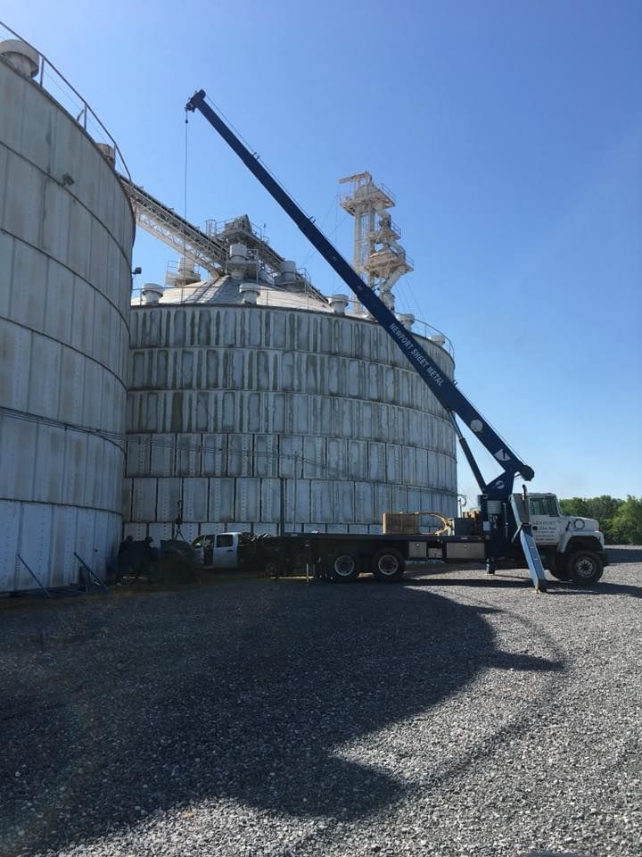 A truck with a crane attached to it is parked in front of a large building.