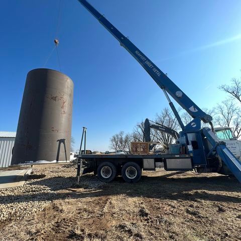 A large cylinder is being lifted by a crane on top of a truck