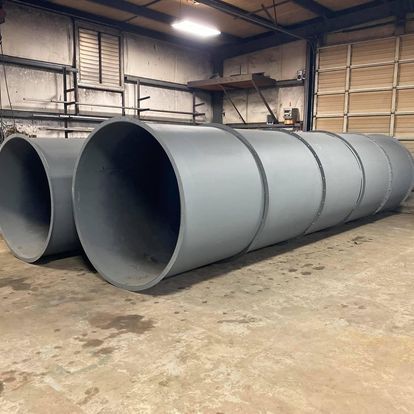 Two large gray pipes are stacked on top of each other in a garage.