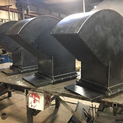 A row of metal ducts are sitting on a table in a factory.
