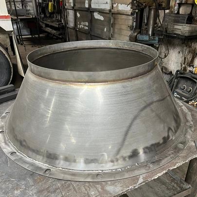 A large metal cone is sitting on top of a metal table.