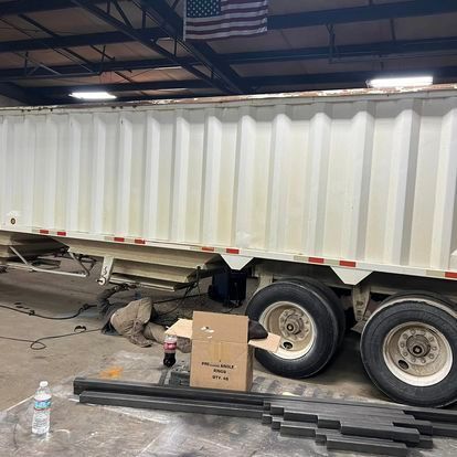 A white semi truck is parked in a garage next to a box and a bottle of water.