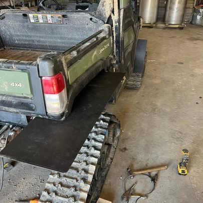 A tractor with tracks attached to it is sitting in a garage.