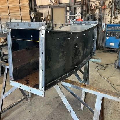 A large piece of metal is sitting on top of a wooden table in a workshop.