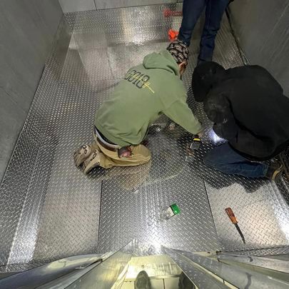 A group of men are working on a metal floor.
