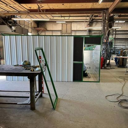 A large room with a green door and a table in it.