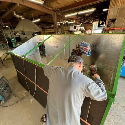 A man is working on a piece of metal in a factory.