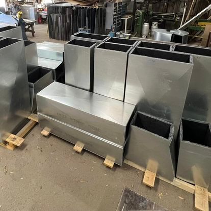 A bunch of metal planters are sitting on top of each other in a warehouse.