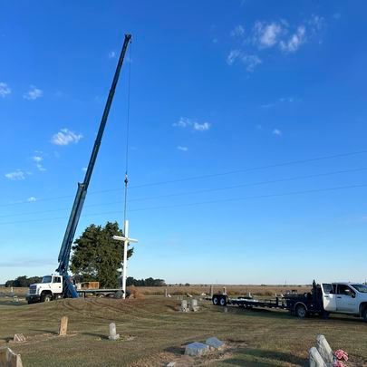A crane is lifting a cross in a cemetery.