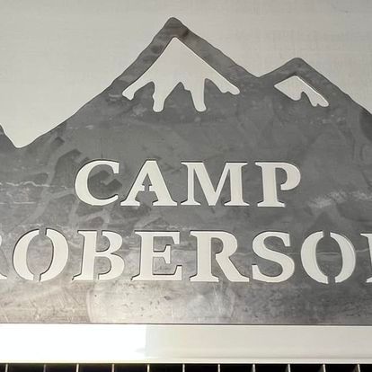 A sign that says camp roberson with a mountain in the background.