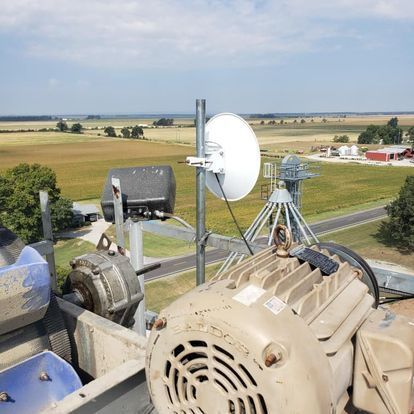 A large motor is sitting on top of a roof next to a satellite dish.
