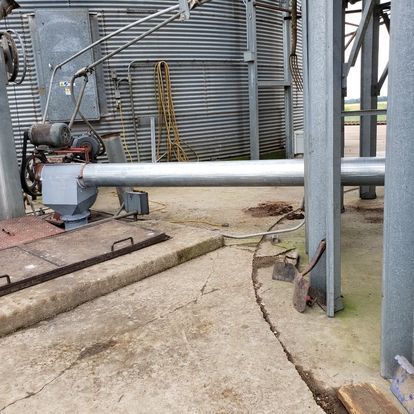 A large pipe is sitting on the ground in front of a building.