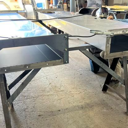 A person is working on a metal table in a workshop.