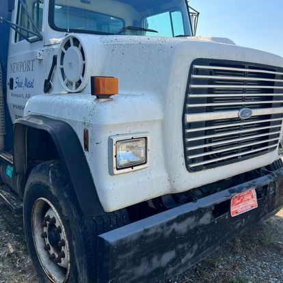 A white ford truck is parked in a gravel lot
