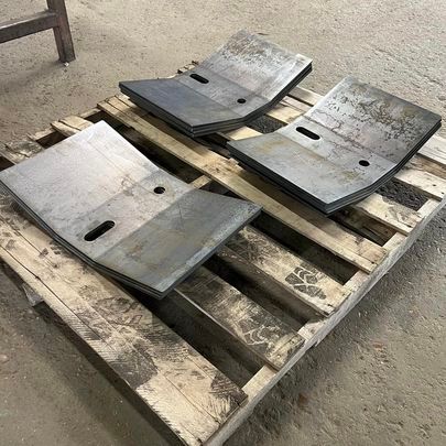 Three pieces of metal are sitting on top of a wooden pallet.