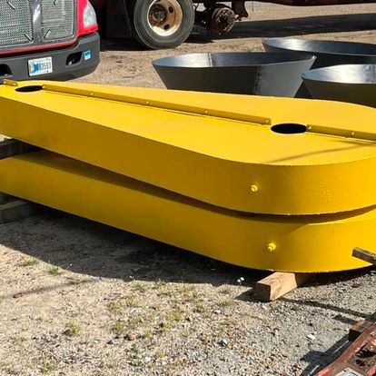 A large yellow object is sitting on top of a wooden pallet next to a truck.