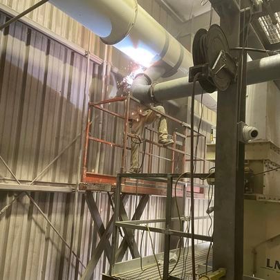 A man is welding a pipe in a factory.