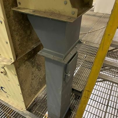 A metal structure is sitting on top of a metal staircase in a factory.