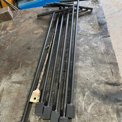 A bunch of metal pipes are sitting on top of a wooden table.