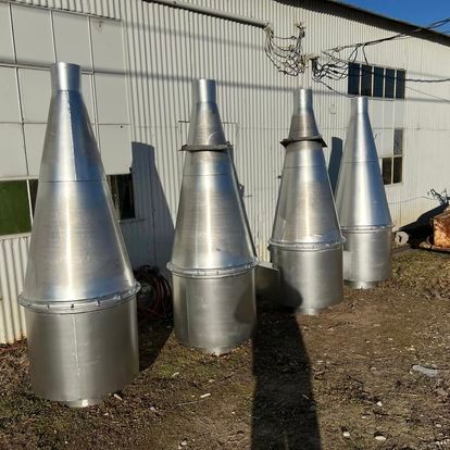 A group of stainless steel cones are sitting in front of a building.