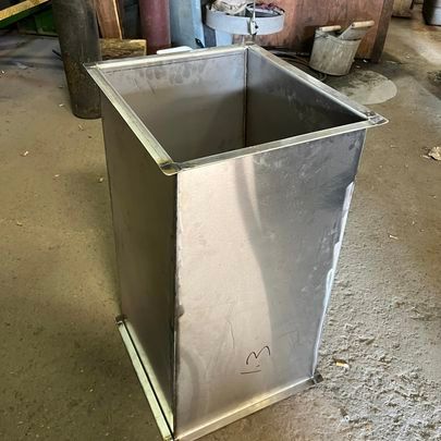 A large stainless steel container is sitting on the floor in a room.