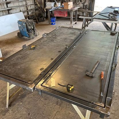 A metal table with a hammer and tape measure on it in a workshop.