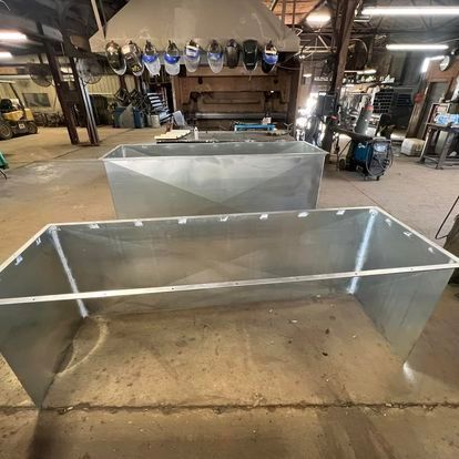 A large metal box is sitting on the floor in a factory.